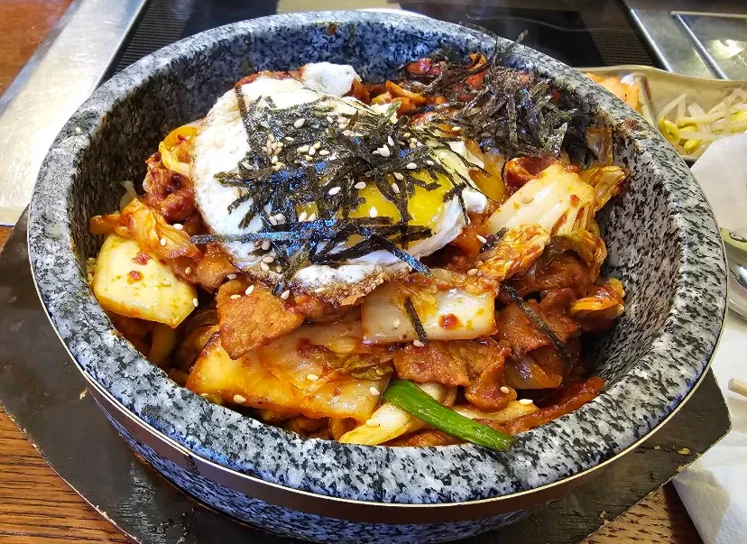 Placeholder photo: a stone bowl of bibimbap topped with a fried egg, seaweed, sesame seeds and kimchi