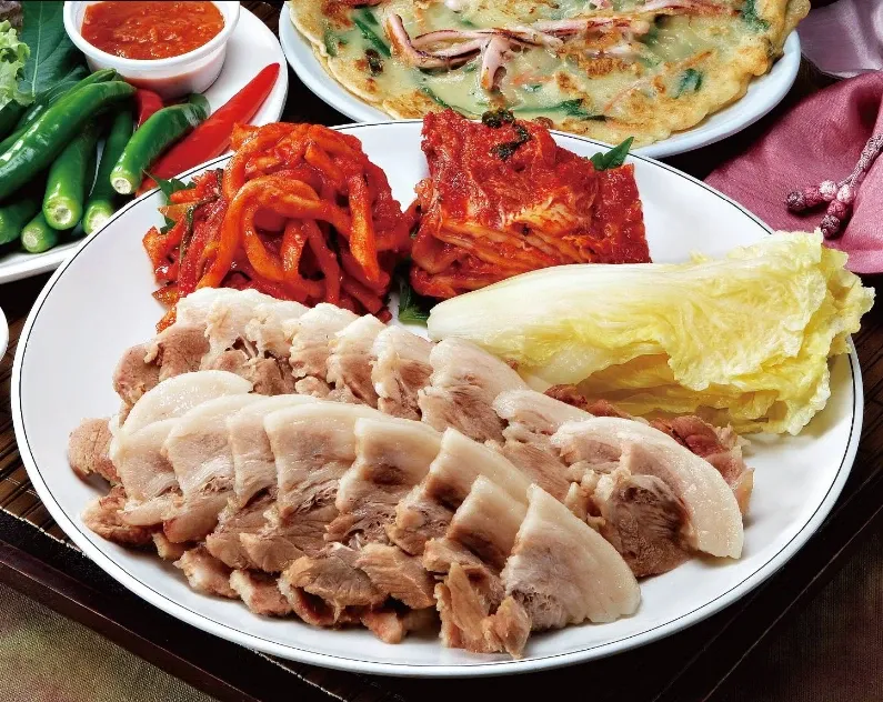 Placeholder photo: sliced boiled pork on a plate with kimchi, cabbage leaves and fresh peppers